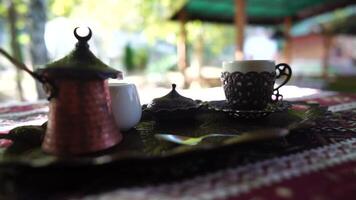 Pouring coffee from cezve, adding frothed milk from pitcher into modern cup by woman's hand. Making traditional coffee with milk. Flat lay with wooden table, stylish coffee details. Slow motion video