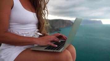 Woman sea laptop. Business woman in yellow hat freelancer with laptop working over blue sea beach. Girl relieves stress from work. Freelance, digital nomad, travel and holidays concept video