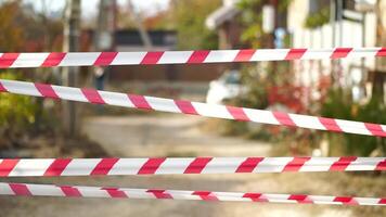 Red and white warning tape swinging in the wind. Protection sign. Don't cross the line. Red White caution tape pole fencing is protects for No entry. Backdrop without people, empty street. video