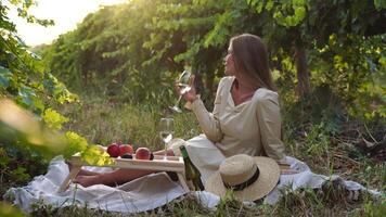 schön Frau mit lange Haar Getränke Weiß Wein von ein Glas beim Sonnenuntergang im das Weinberg. ein Frau Hand schüttelt ein Glas von Weiß Wein leicht. Wein Verkostung und Wein Herstellung Konzept. schleppend Bewegung video