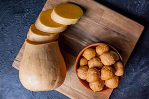 Freshly fried pumpkin fritters in a bowl on a board. photo