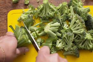 manos corte brócoli repollo. sano verde vegetales. foto