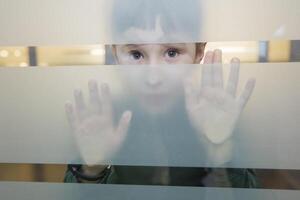 The child is looking through the glass. Boy peeps in frosted glass photo