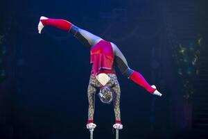 A gymnast performs in a show. A girl gymnast performs a circus acrobatic performance. photo