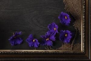 Part of a beautiful frame contains rough weave fabric on a wooden background and violet flowers. Background for the inscription. photo