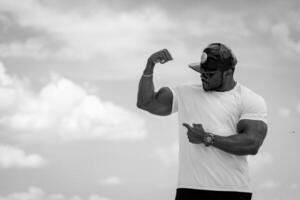 Strong muscular man showing his muscles. Black and white shot of bodybuilder. photo