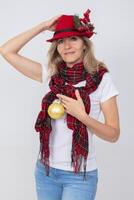 A beautiful adult woman in a Christmas red hat holds a golden fir ball. photo