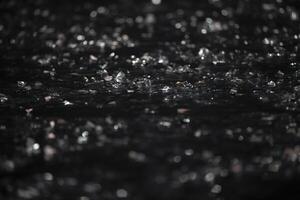 On a black background there are silver bokeh spots from shiny confetti. photo