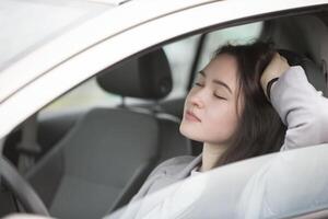 Young tired girl with car eyes closed. Beautiful dreamy woman driving photo