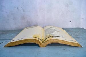 a thick book open on a table against a plain white wall background, Indonesia, 30 October 2023. photo