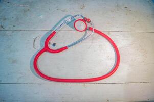 A red stethoscope on a wooden table photo