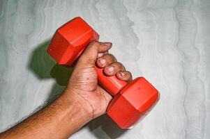 hands holding a red dumbbell with full force photo