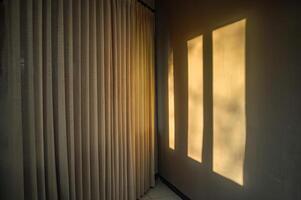 the shadow of the window on the wall with the window covered with curtains in the morning photo