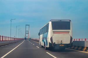 un antiguo entre ciudades autobús ese pasa en el suramadu puente a madura en Surabaya, Indonesia, 17 noviembre 2023. foto