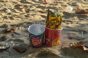 instant noodle cup packaging littering the beach sand, Indonesia, 2 October 2023. photo