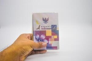 hand holding an Indonesian passport isolated on a white background, Indonesia, 2 January 2024. photo