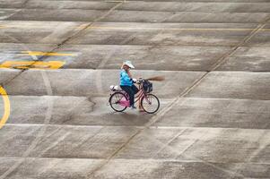 a female janitor at Juanda International Airport is riding a bicycle while carrying a broom on the airport apron, Indonesia, 6 January 2024 photo