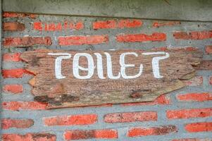 un de madera firmar ese dice baño es adjunto a un ladrillo pared foto