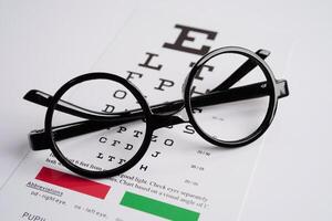 Glasses on eye exam chart to test eyesight accuracy of reading. photo