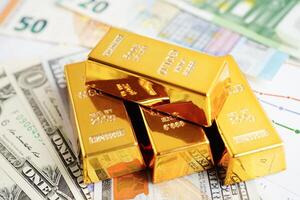 Gold bars with US dollar and Euro banknote money, finance trading investment business currency concept. photo