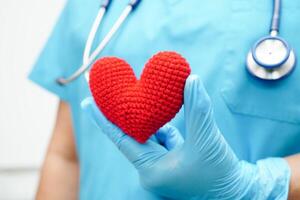 Asian woman doctor holding red heart for health in hospital. photo