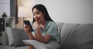 Footage dolly shot, Happy young woman sitting on sofa enjoy using mobile phone for online shopping cashless in living room at home video