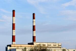 Two factory pipes of a thermal power plant against the blue sky photo