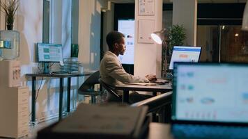 Bipoc coworkers auditing financial payroll reports and statistics on computer screen during nightshift. Adept businessmen working overnight on important project due tomorrow photo