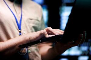 Meticulous technician doing checkup, inputing data on tablet of needed fixes in server hub housing advanced data storage infrastructure supporting critical IT workloads, close up photo