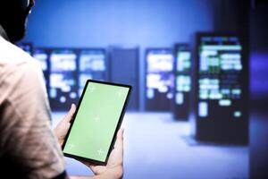 Computer scientist using green screen device to verify data center hardware configuration. Serviceman looking at monitoring software program to troubleshoot defective server mainframes root cause photo