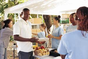 Multiracial hunger relief group working outdoors to donate free meals and essential items to homeless people. Non-profit organization provide assistance to poor, needy and less fortunate individuals. photo