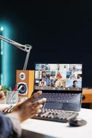 Detailed view of laptop screen displaying group of people on a video conference call. African American person working at home, having virtual communication with coworkers on wireless computer. photo