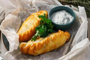 Baked buns with sour cream and parsley on parchment paper photo