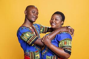 Smiling mid adult spouse hugging and looking at camera with cheerful expression. Wife and husband romantic couple embracing, showing happiness and posing for studio portrait together photo