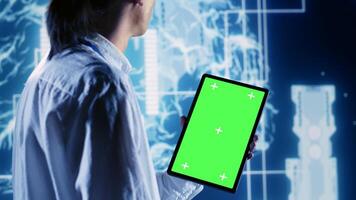 Skillful IT consultant using green screen tablet to implement artificial intelligence parallel processing. Dilligent supervisor oversees chroma key device enabling AI to do machine learning inference photo