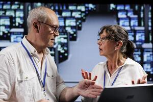 Octogenarian employees working to maintain uptime in high tech workspace. Efficient workers brainstorming solutions to data center blade servers crashing, trying to fix components photo