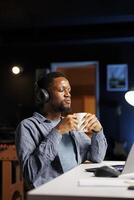 Young adult attends training online program from home, listening to teacher explaining business administration terms. African american student learning management, listening to podcast. photo