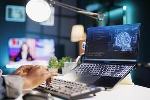 Black person typing on bluetooth keyboard and computing code on laptop to build databases. Close-up of a black individual working from home while looking at data center and software system. photo