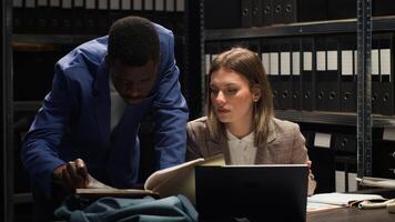 African american inspector carrying files and evidence to female investigator for discussion. Multiethnic police partners analyzing clues and conducting investigations to solve organized crime. photo