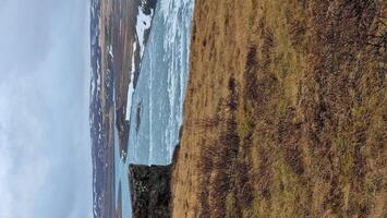 Gullfoss cascade in icelandic frosty region, fantastic nordic scenery with snow covered hills and freezing cold water falling off edge. River stream flowing on top of cliffs, natural waterfall. photo