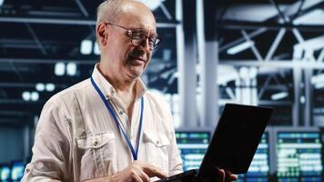 Organized professional navigating network of server equipment in industrial hub. Serviceman with laptop doing optimizations and maintenance in data center, preventing system issues photo