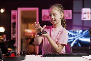 Happy young girl in studio reviewing gaming mouse in front of camera in personal studio. Cheerful kid filming electronics haul, presenting wired computer peripheral to viewers photo