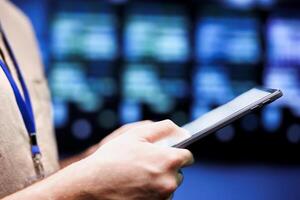 Close up shot of computer scientist using tablet to check server hub security features protecting against unauthorized access, data breaches, ddos attacks and other cybersecurity threats photo