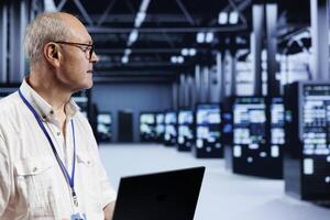 Qualified specialist using laptop, setting up high bandwidth dedicated multiplayer gaming servers in supercomputer farm to accommodate more traffic from worldwide locations and avoid disruptive lag photo