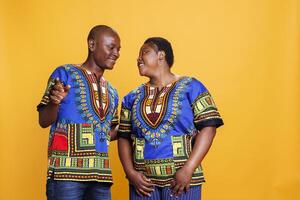 Happy black man and woman couple dancing and making moves together. Smiling wife and husband looking at each other with cheerful and romantic expression and posing in studio photo