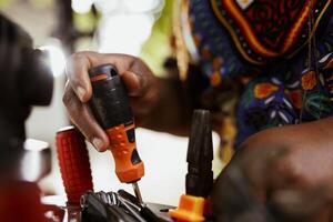 Closeup shot of african american hands grasping bicycle tools from professional toolbox for maintenance and repairs. Detailed image of individual arranging specialized equipments. photo