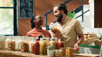 Seller helping people with information about homegrown products and sustainable lifestyle, presenting organic natural vegetables. Couple looking for vegan food alternatives at local eco store. photo