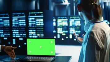 Engineering coworkers using mockup laptop to implement artificial intelligence parallel processing. Adept colleagues work on green screen device, enabling AI systems to process machine learning data photo