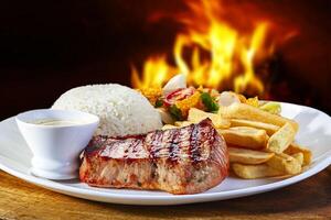 Grilled pork steak with rice, french fries and salad photo