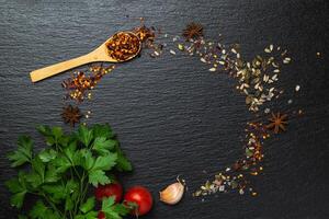 Different kind of spices frame on a black stone background photo